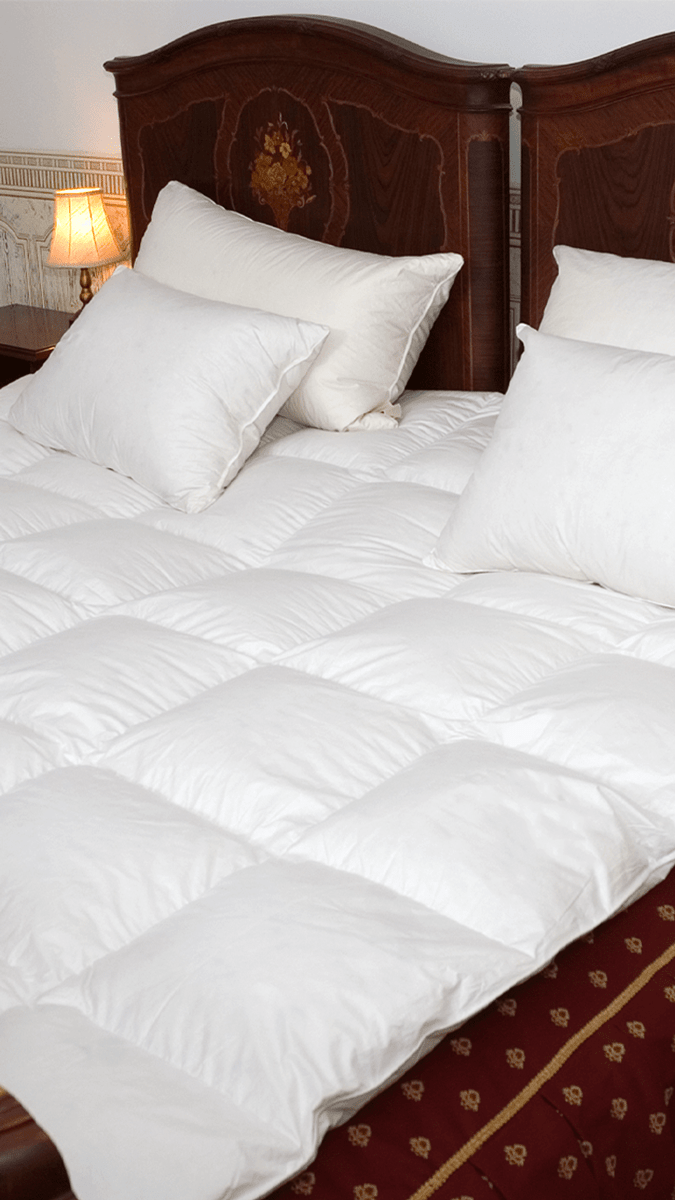 a bed with white goose down comforter and down pillows